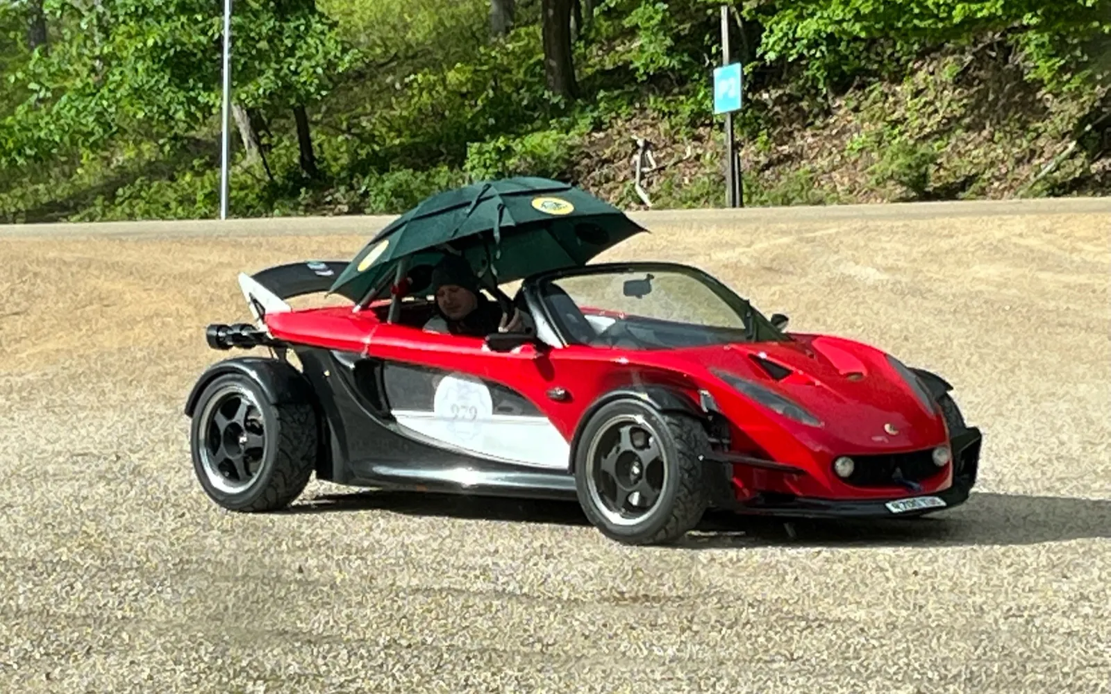 Piros Lotus 340R a depóban, esernyő alatt